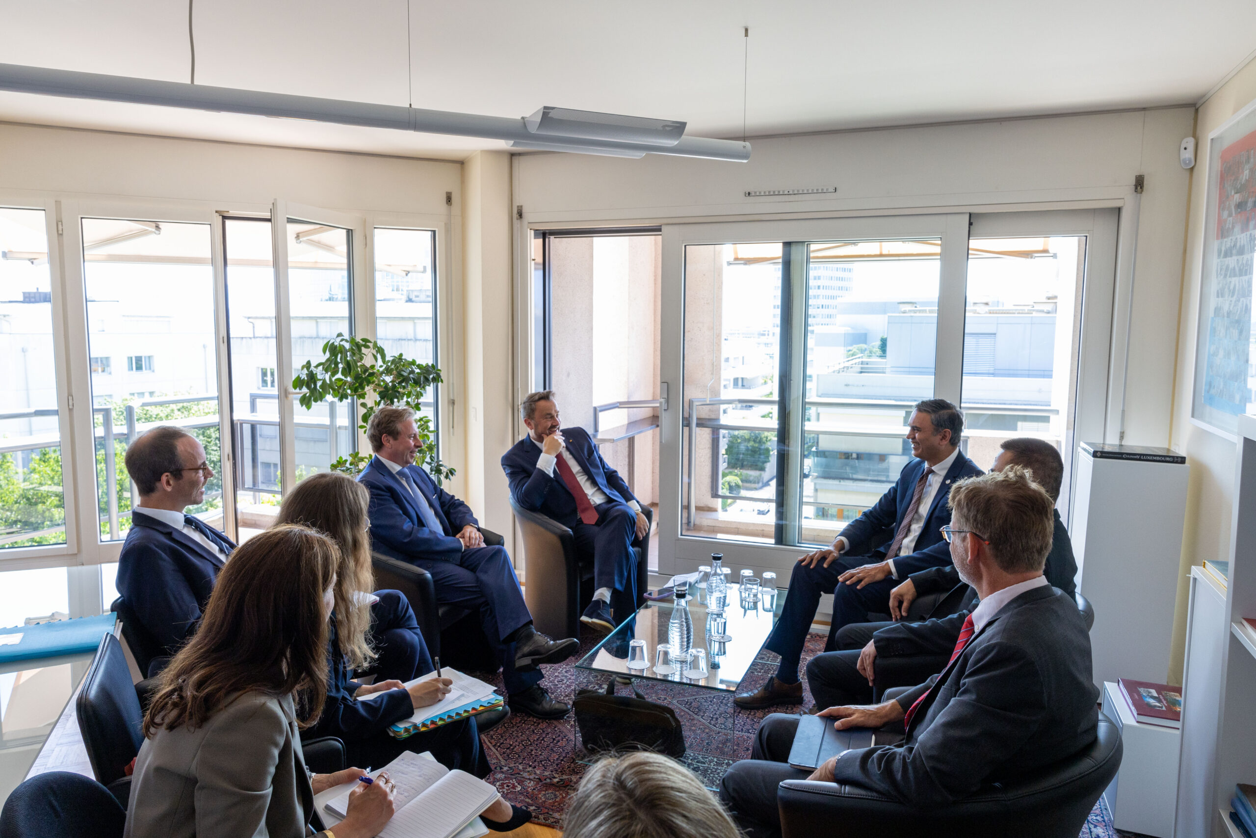 A group of officials and representatives from Luxembourg and UNICC seated in a bright office, taking notes and discussing.