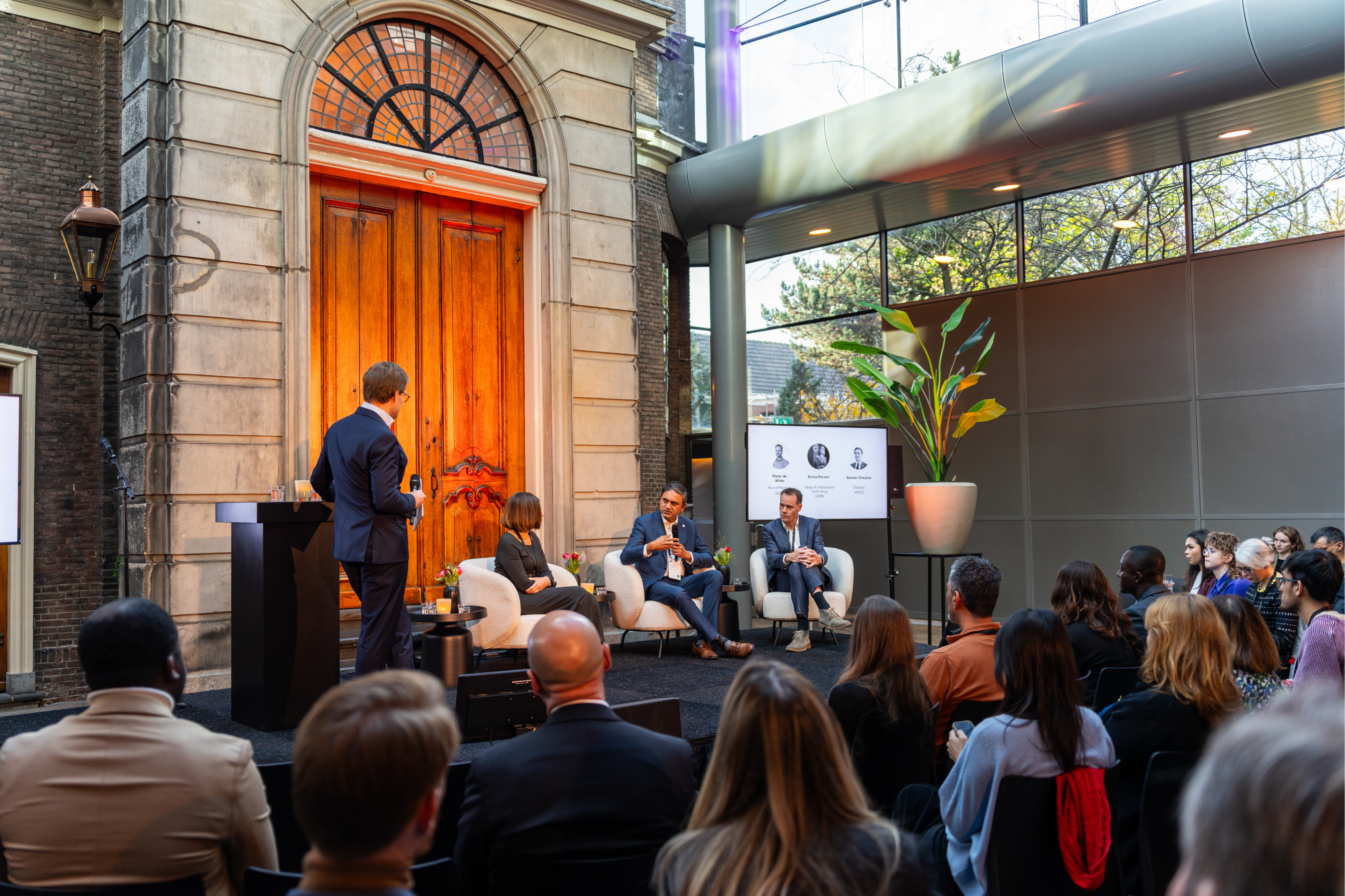 A fireside panel featuring Enrica Porcari, Head of Information Technology at CERN; Sameer Chauhan, Director of UNICC; and Pieter de Witte, Board Member at Quantum Delta NL, engaged in a discussion moderated by Diederick Croese, Director of the Centre for Quantum and Society at Quantum Delta NL.